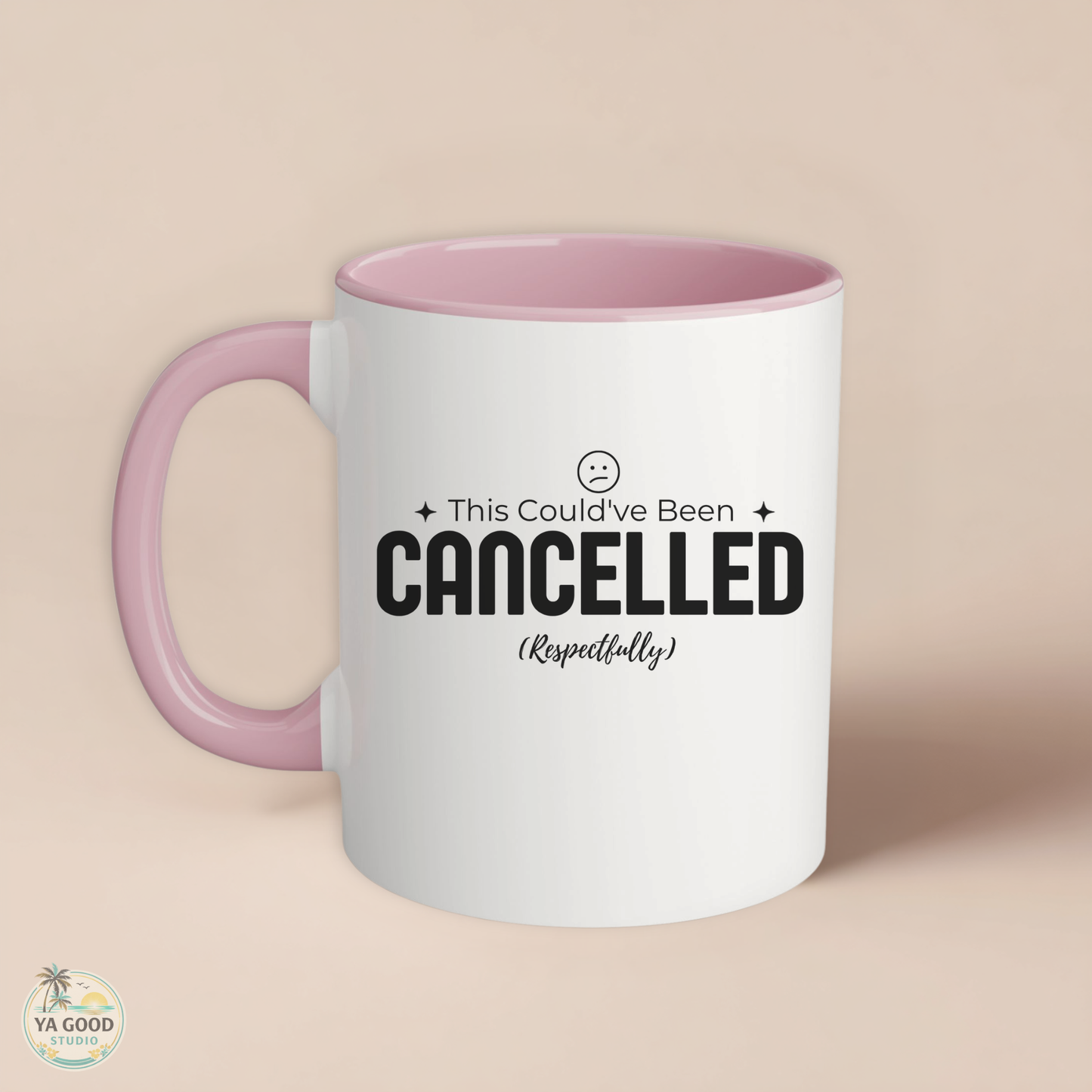 White mug with pink handle and 'This Could've Been Cancelled' text on a beige background