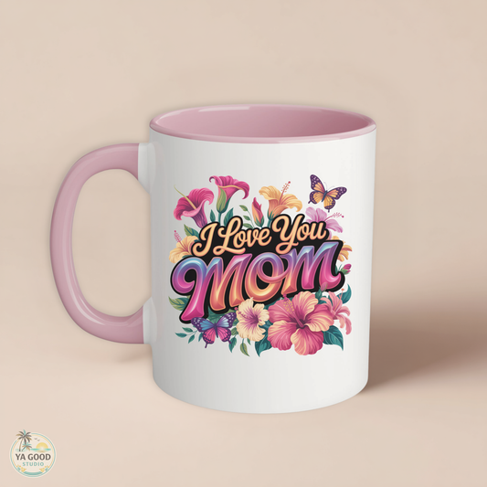 white mug with pink trim that says "I Love you Mom" in floral pattern on beige background