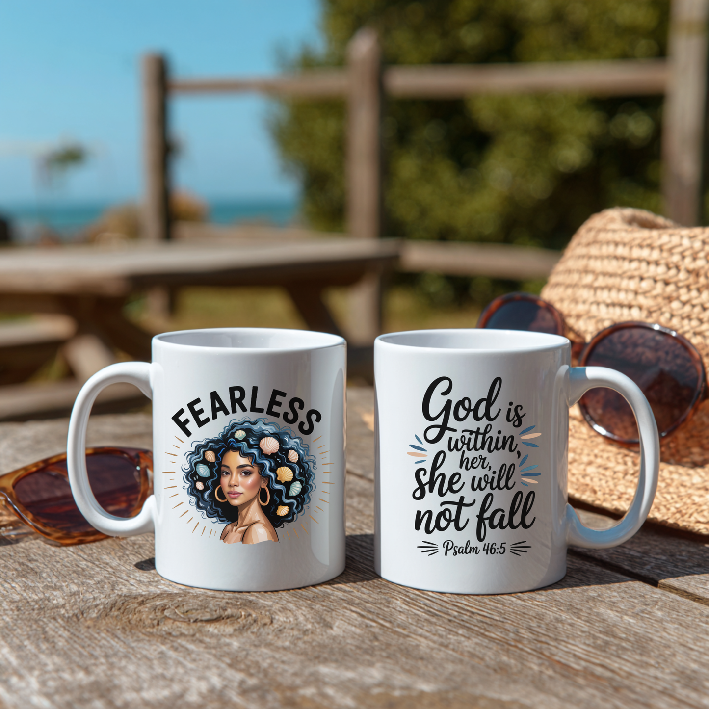 A white mug showing both sides. One side has the word fearless with a design and the other has a bible verse. The mugs are on a wooden surface outdoors.