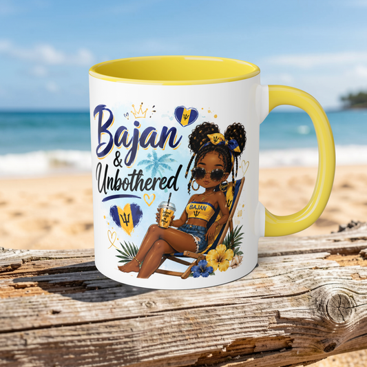 Mug with a design of a woman sitting on a beach, text 'Bajan & Unbothered', and Barbadian flag on a wooden surface with ocean background.