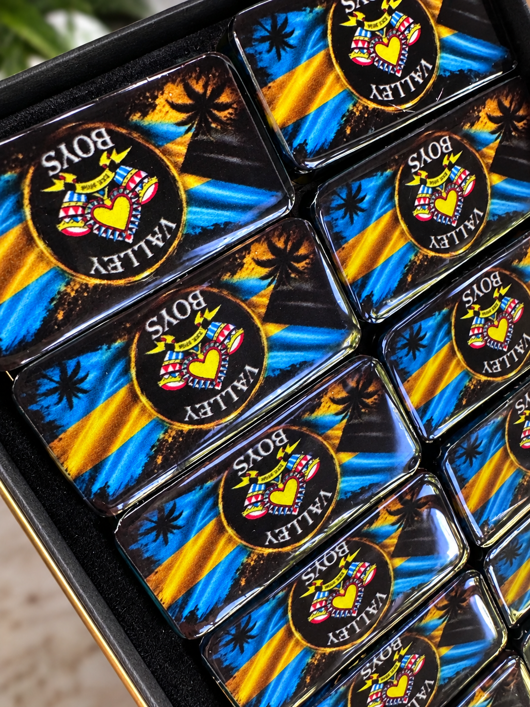 Close-up of glossy handmade resin dominoes with colorful Junkanoo artwork