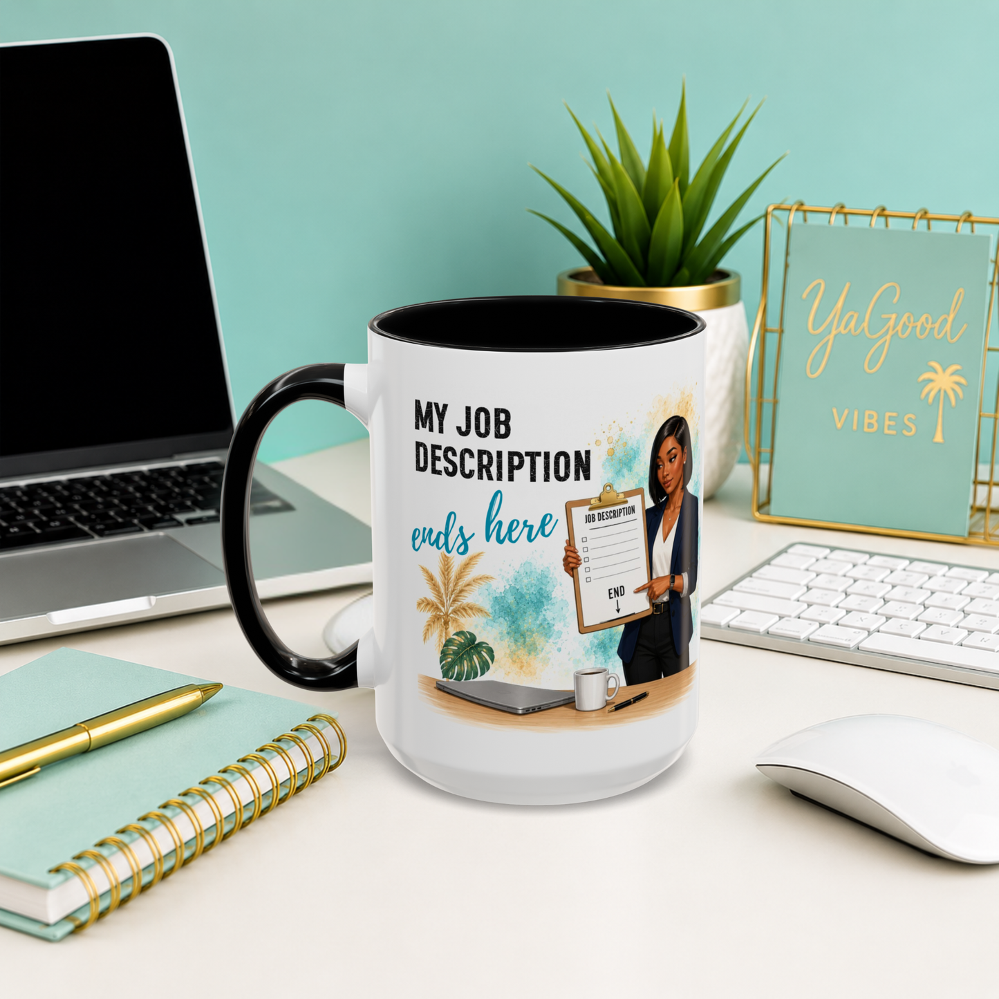 A white ceramic mug with a black handle and interior, printed with a humorous job description graphic, displayed on a desk in a styled office setting.