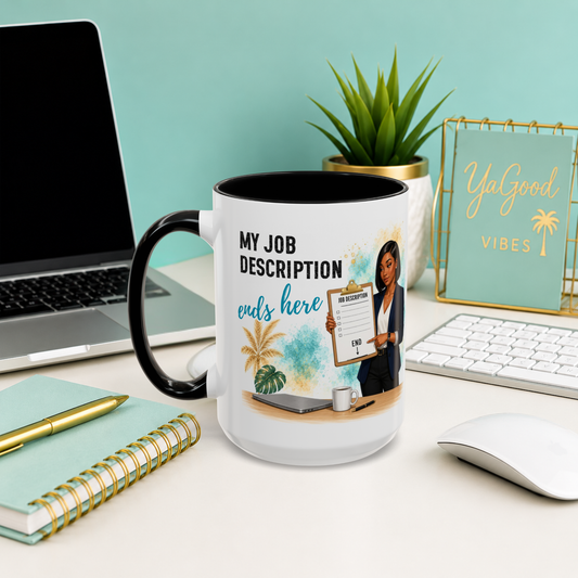 A white ceramic mug with a black handle and interior, printed with a humorous job description graphic, displayed on a desk in a styled office setting.