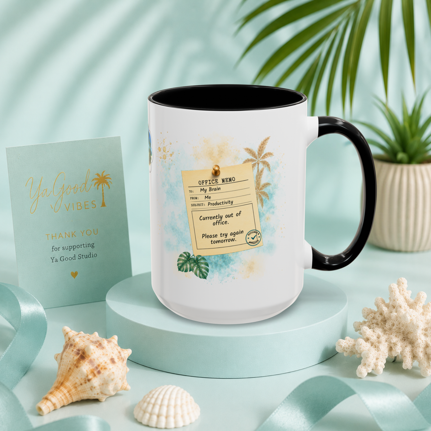 A white ceramic mug with a black handle and interior, decorated with a tropical office departure-style ticket graphic featuring palm trees and watercolor accents. The mug is styled on a light blue pedestal with seashells, a thank-you card, ribbon, and a potted plant in the background.
